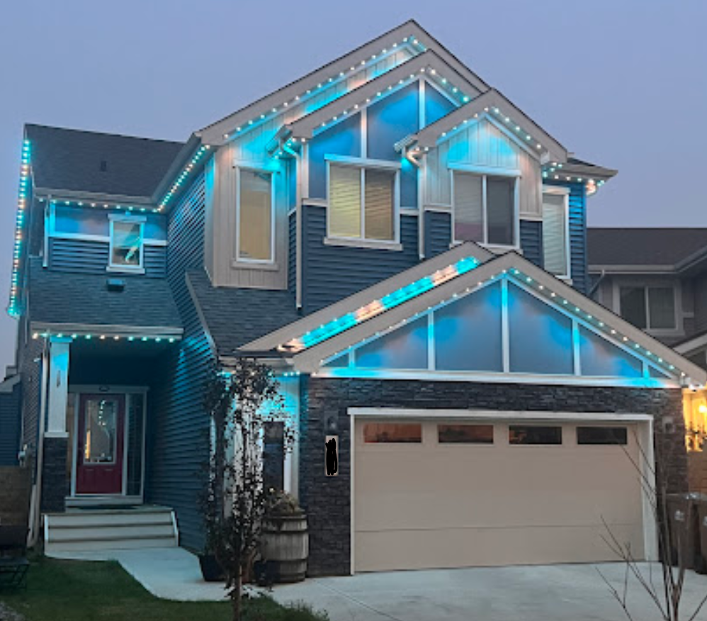 A home with one of Darren Does That's Watts Smart Light installations currently glowing in teal and pure white. This home has a very intricate roofline with multiple compound gables, meaning the cost to install permanent lights would be on the higher end.