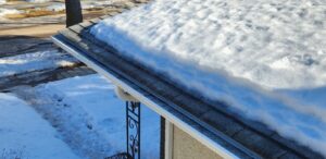 picture taken of a roof during a Darren Does That Spring Inspection that shows 1.5" of ice under a pack of snow on the eave  