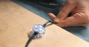 Closeup of a Watts puck, the best Permanent Christmas Lights having been struck by the blunt side of a hatchet five times, showing the blue lighting channel still intact and minimal deformation to the epoxy coating.