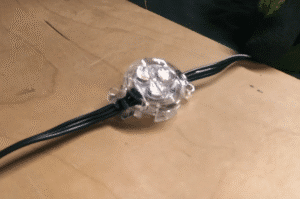 A close up of a Watts Permanent Christmas Light after being struck with the blade of a hatchet 8 times showing how resistant the epoxy is to damage.