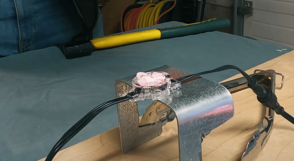 A Watts Permanent Christmas Lighting Puck shows deformed, but intact epoxy after being subjected to greater than 140 degree Celsius temperatures in a stress test in the Darren Does That garage in Edmonton.