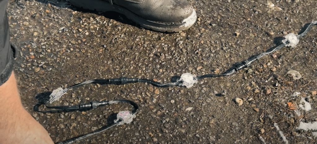 A String of Watts Permanent Christmas Lights is on the asphalt on a back alley in Edmonton, completely intact after being run over with a van.