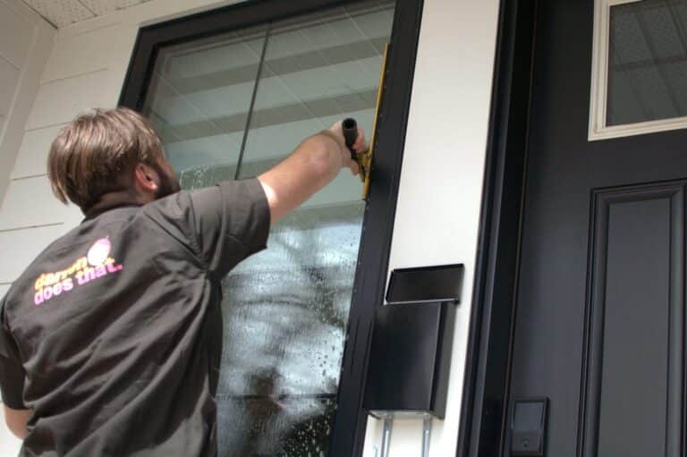 A window cleaner cleans a large window with a Squeegee.